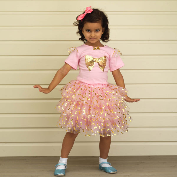 Girl in pink short sleeve tutu & top set decorated with gold bow and sequins.