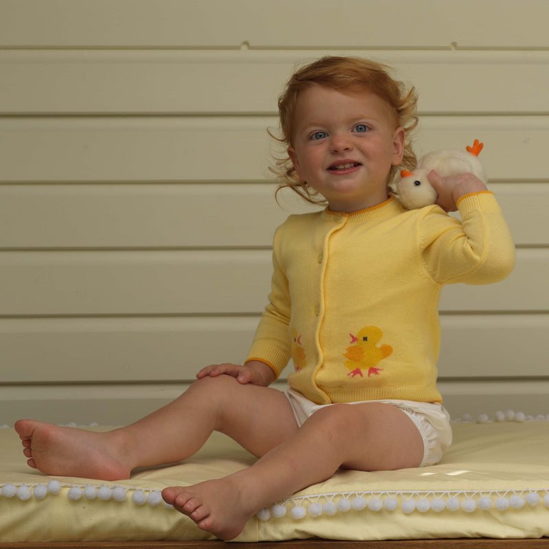 Baby wearing chick intarsia design cardigan with yellow background and white bloomers