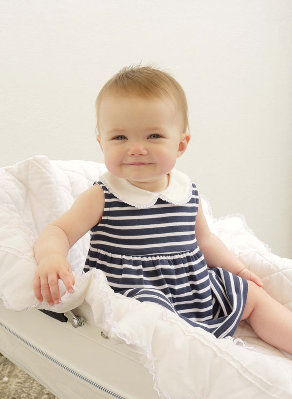 Baby girl wearing navy sleeveless breton stripe jersey dress.