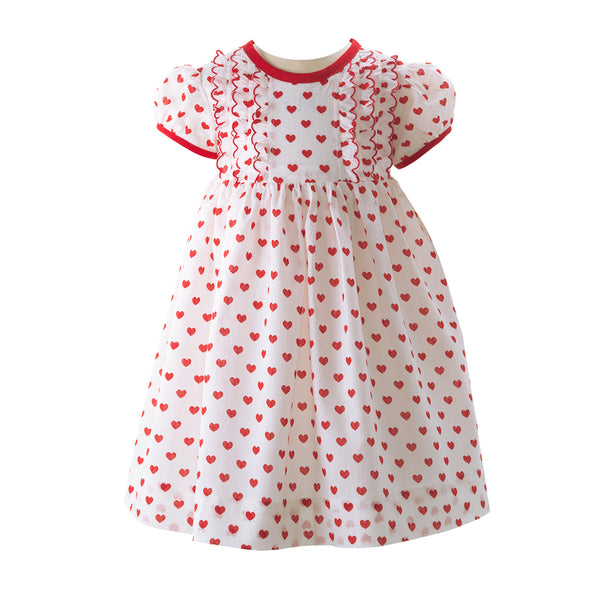 Baby ivory dress with red heart print and frill detail at the bodice, red trim and sash tie
