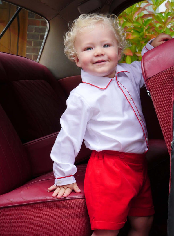 Baby boy wearing red babycord short and white pique shirt set.