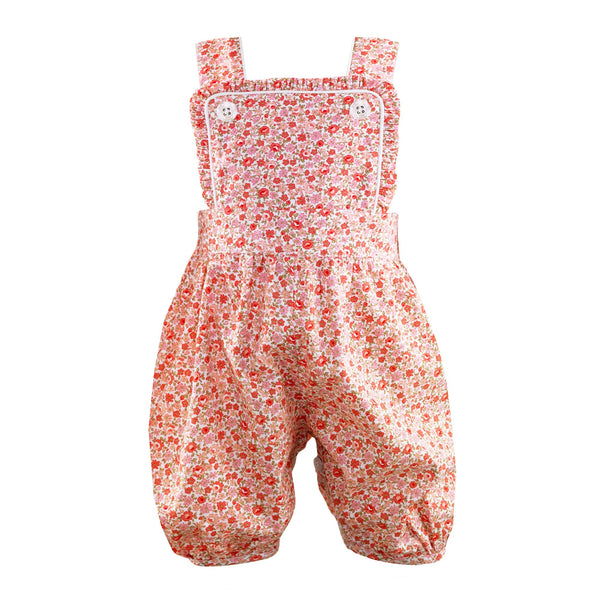 Coral pink frill dungarees with floral print and ivory piping trim, and adjustable crossover straps.