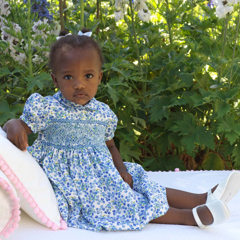 Baby in blue floral dress with hand-smocked bodice, peter pan collar and gathered skirt.