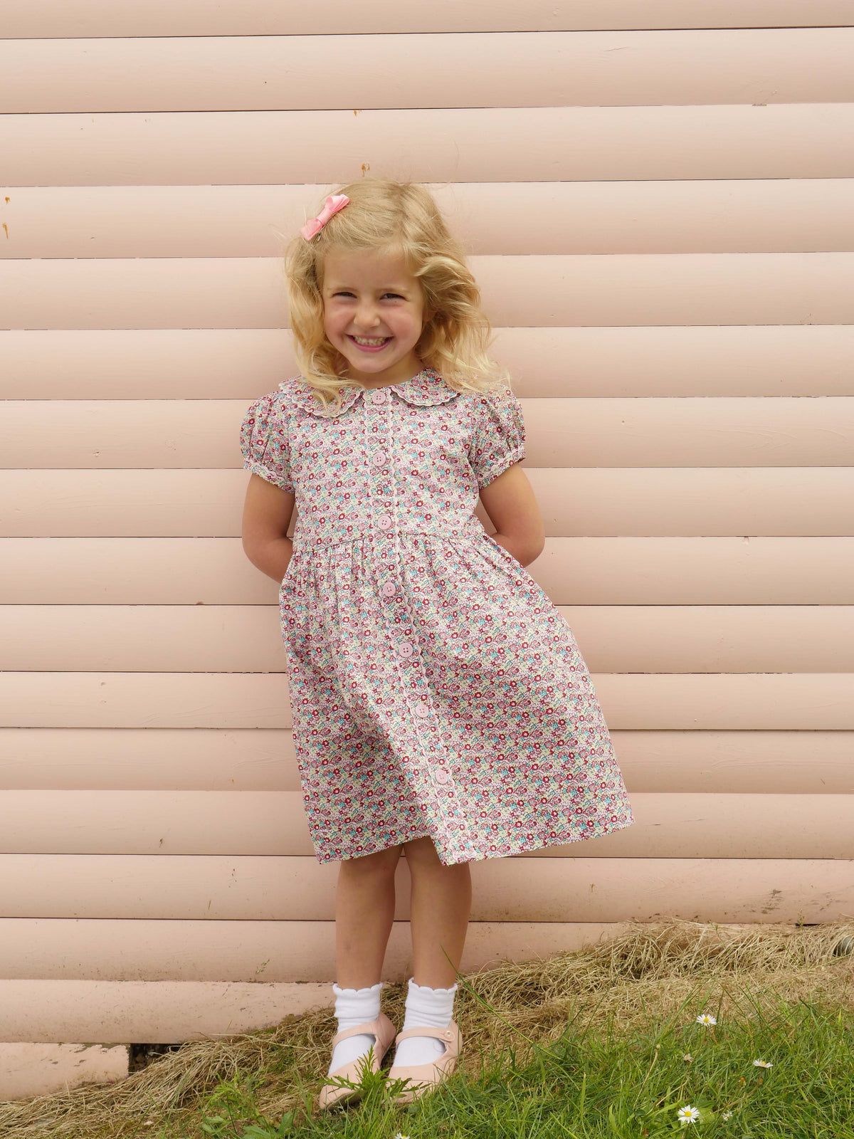 Girl in ditsy floral button-front dress with puff sleeves, coordinating ricrac trims and buttons.