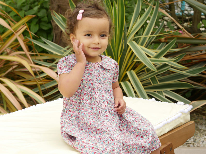 Baby in ditsy floral button-front dress with puff sleeves, coordinating ricrac trims and buttons.