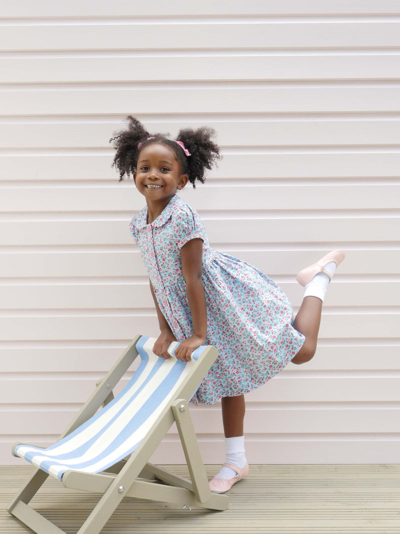 Girl in blue floral button-front dress with puff sleeves, matching ricrac trims and buttons.