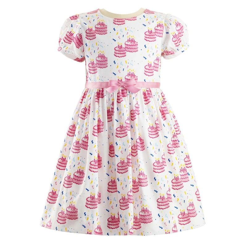 Puff sleeved party dress with a pink birthday cake print and pink ribbon and bow at waist.