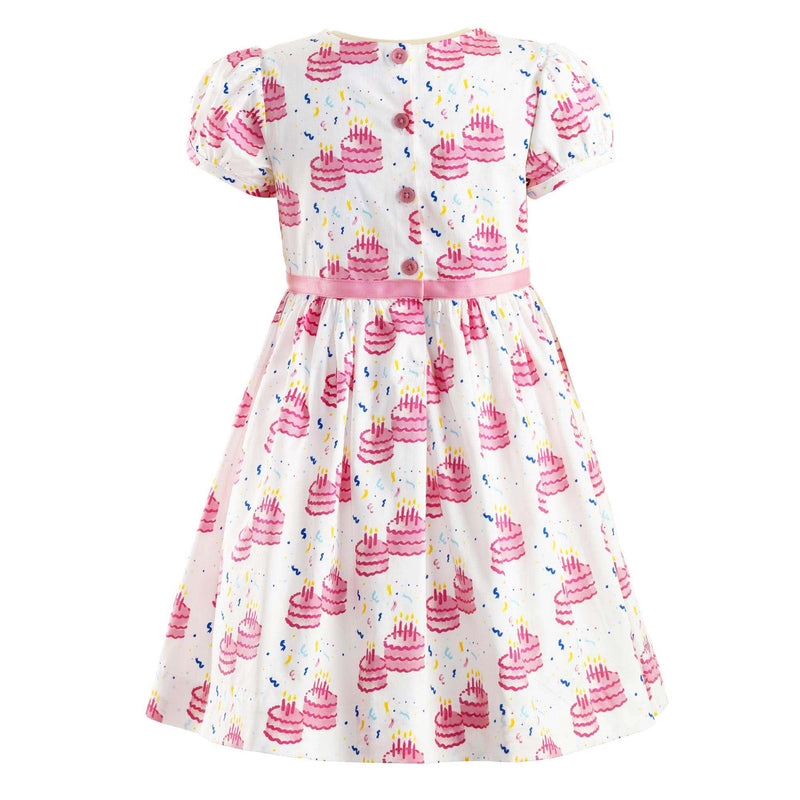 Puff sleeved party dress with a pink birthday cake print and pink ribbon and bow at waist.