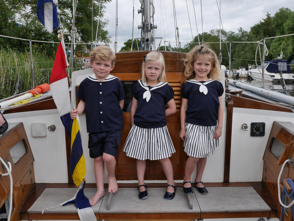 Girls in cotton skirt with navy and white stripes and matching sailor jersey top.