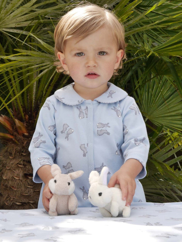 Baby wearing soft cotton babygro with grey bunnies print on blue base.
