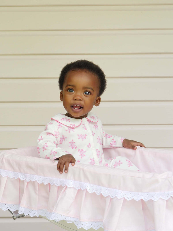 Baby girl wearing pink teddy babygro with pink teddy print and pink picot trimmed peter pan collar.