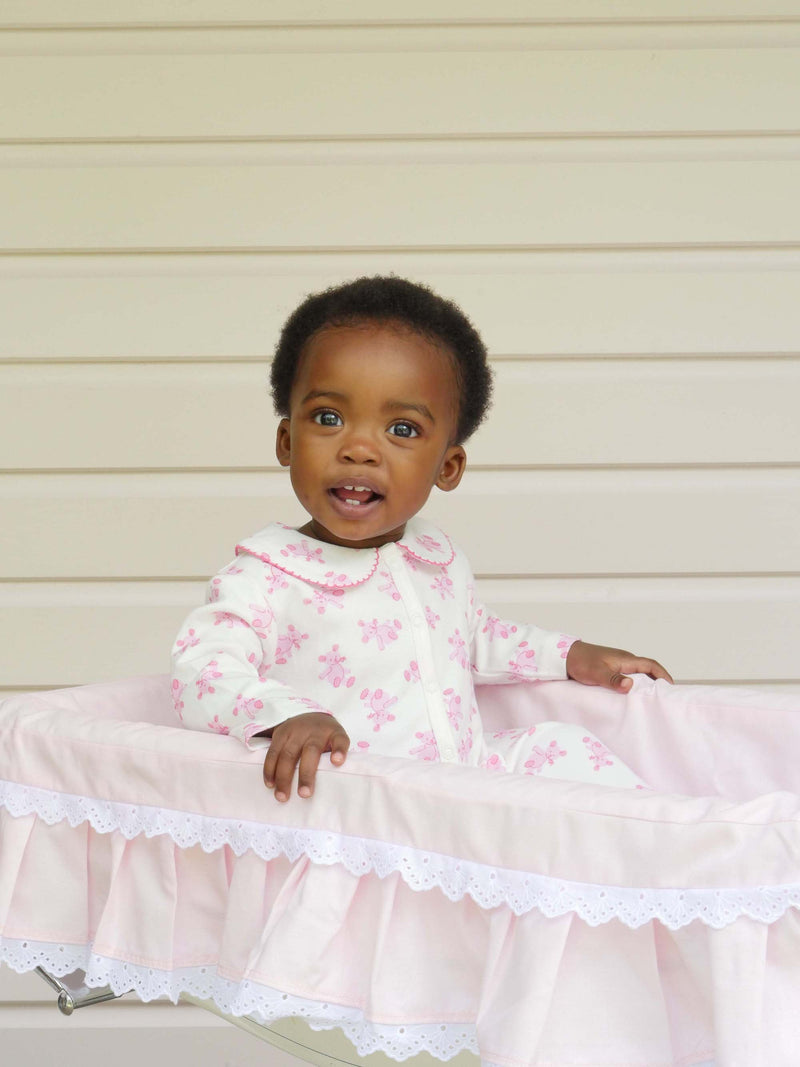 Baby girl wearing pink teddy babygro with pink teddy print and pink picot trimmed peter pan collar.