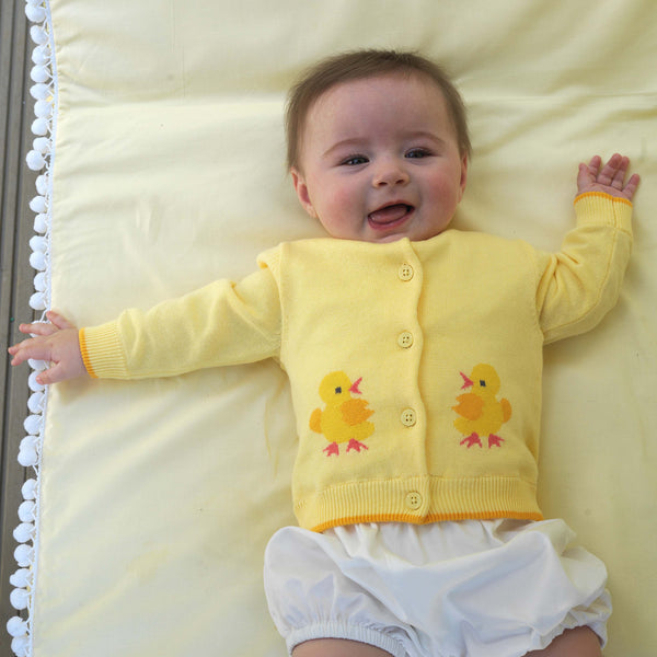 Baby wearing chick intarsia design cardigan with yellow background and white bloomers