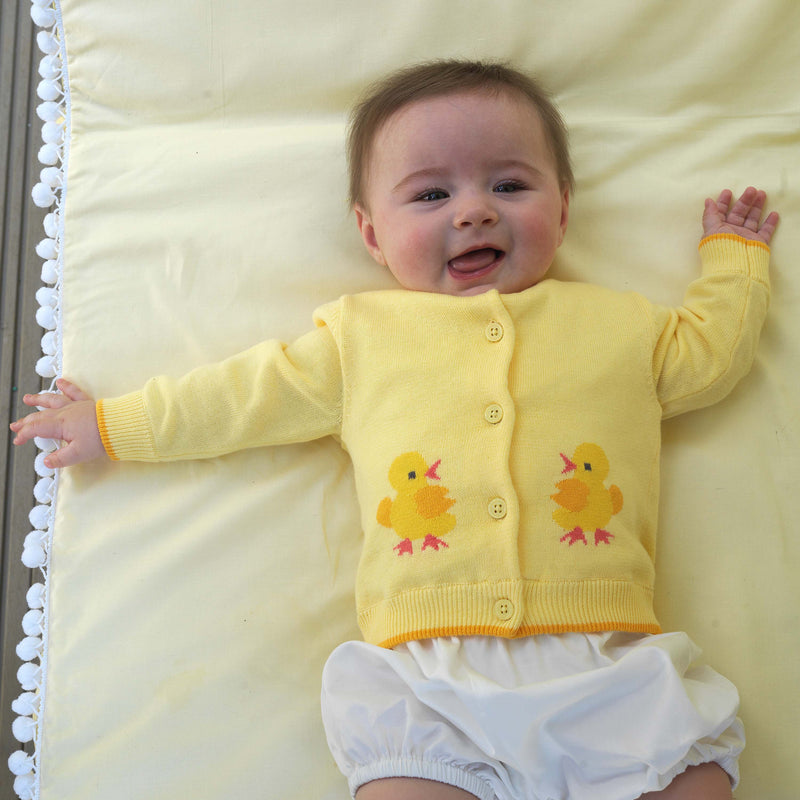 Baby wearing chick intarsia design cardigan with yellow background and white bloomers