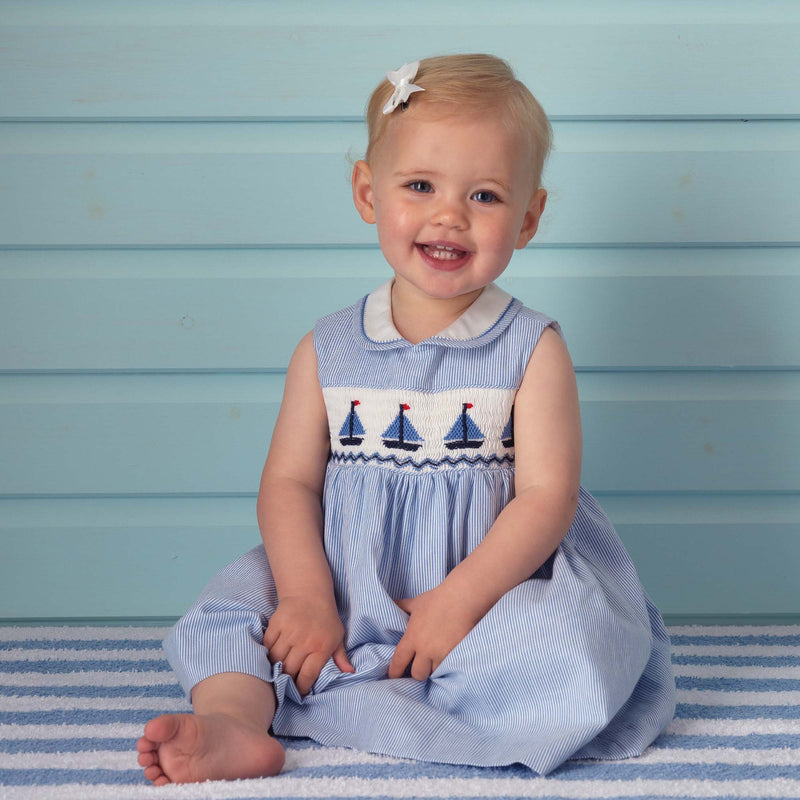 Baby girl wearing sailboat smocked dress and white hairbow