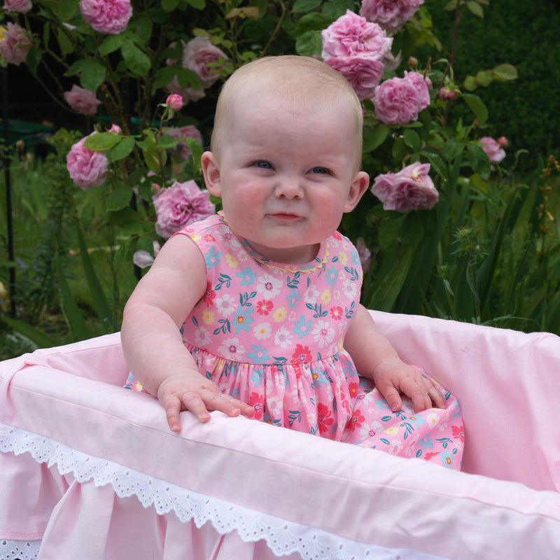 Baby wearing pink flower fields dress and bloomers.