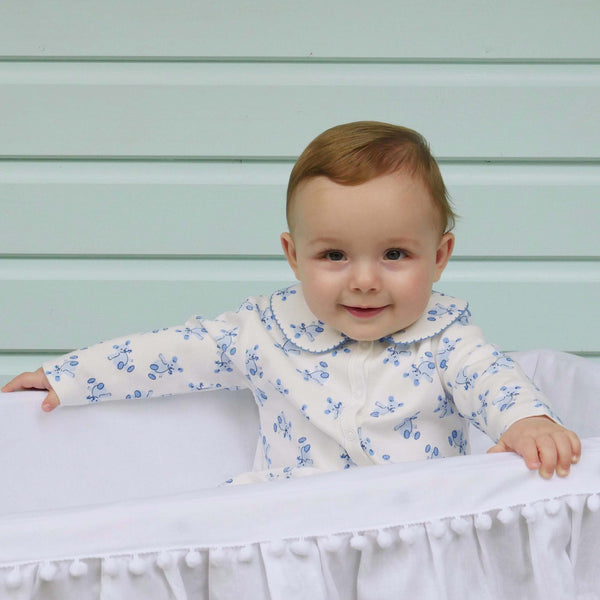 Baby wearing soft cotton babygro with blue teddy print on white base.
