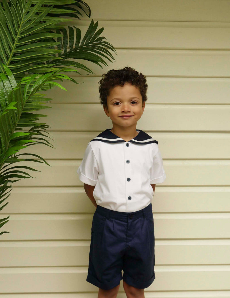 Boy in navy tailored shorts and ivory sailor jersey shirt.