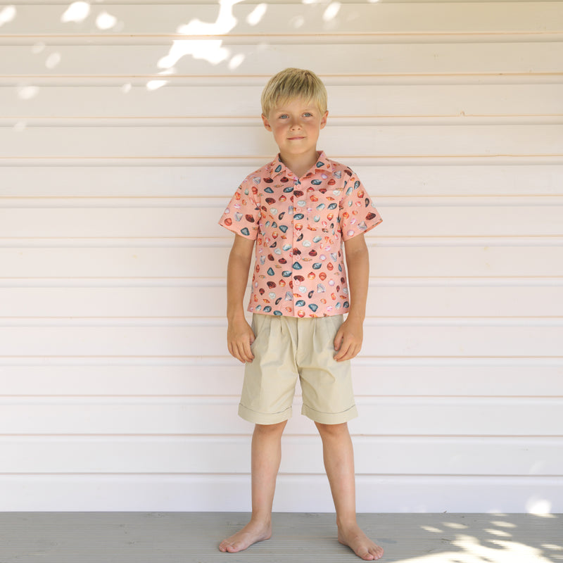 Boy wearing sandy beach print styled with beige tailored shorts.
