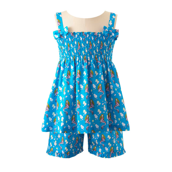 Girls ruched top with bows on straps and matching shorts with mermaid print on deep blue background.