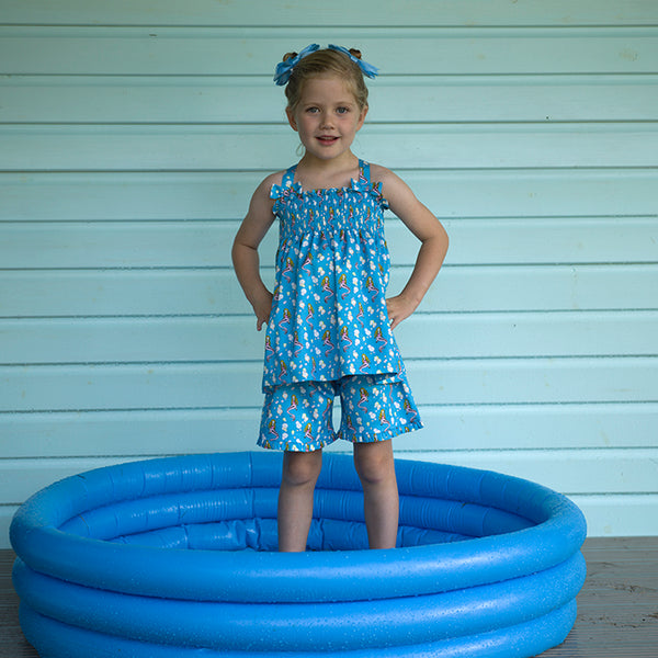 Girl wearing blue mermaid short set with complimenting blue hairbows.
