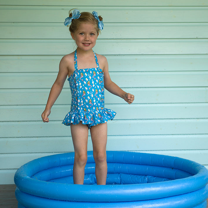 Girl wearing blue mermaid ruched swimsuit styled with matching blue hairbows.