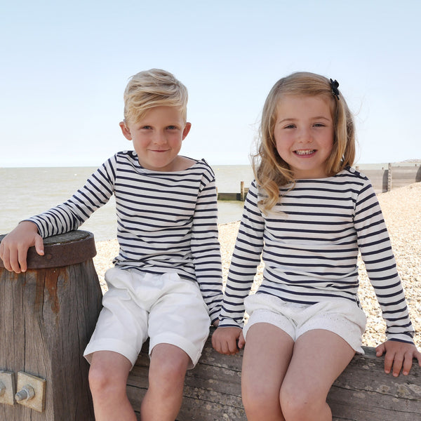 Girl and boy wearing matching navy striped jersey top styled with white shorts