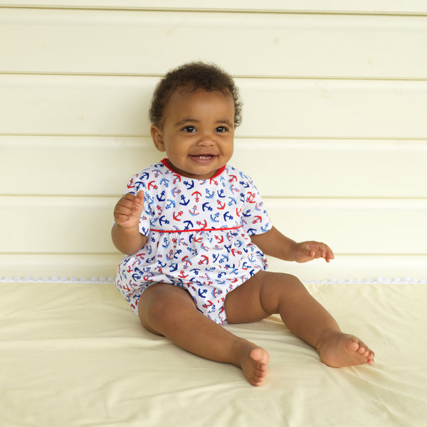 Baby wearing red and blue anchor print babysuit.
