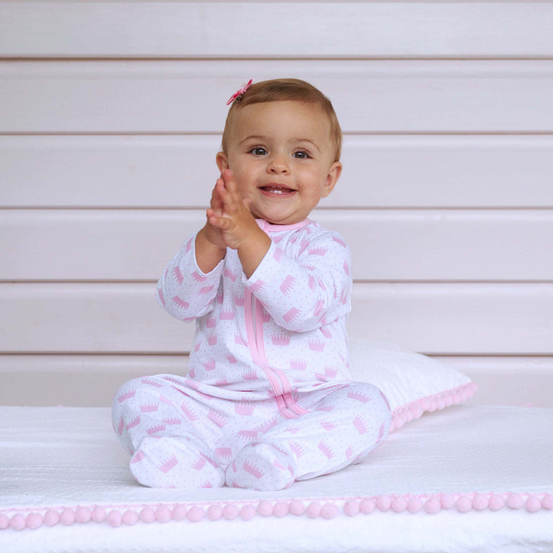 Baby girl wearing pink polka dot crown babygro and pink hairbow.