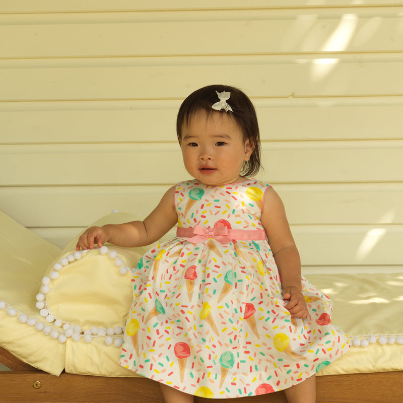 Girl wearing Ice cream pleated dress styled with matching hairbow and slippers.