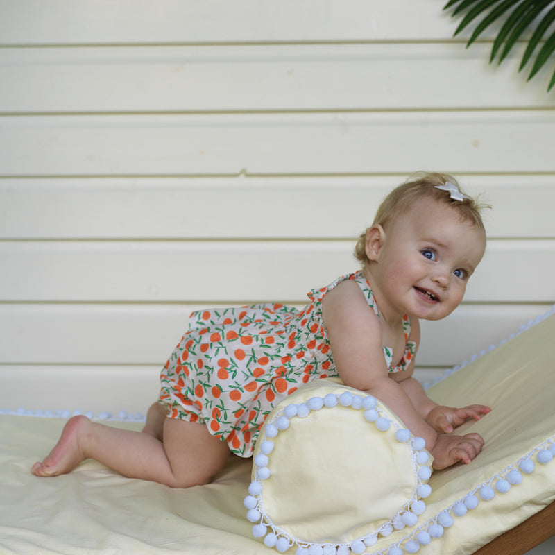 Baby girl wearing peach tangerine print top and shorts set with matching hairbows.