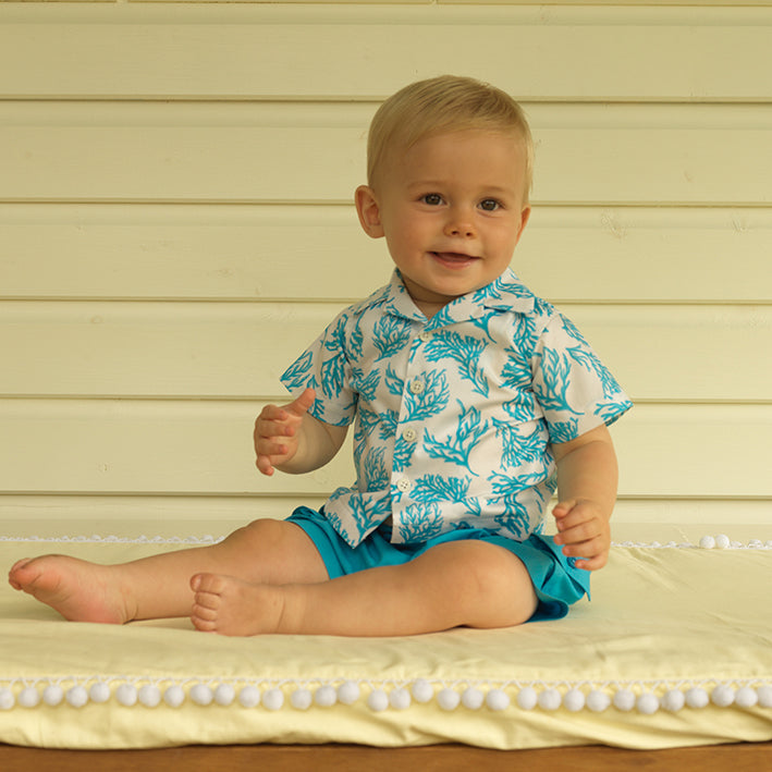 Baby boy wearing aqua coral print shirt styled with aqua pocket shorts.