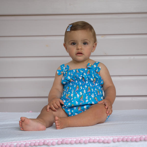 Baby girl wearing blue mermaid bubble swimsuit with matching hairbow.