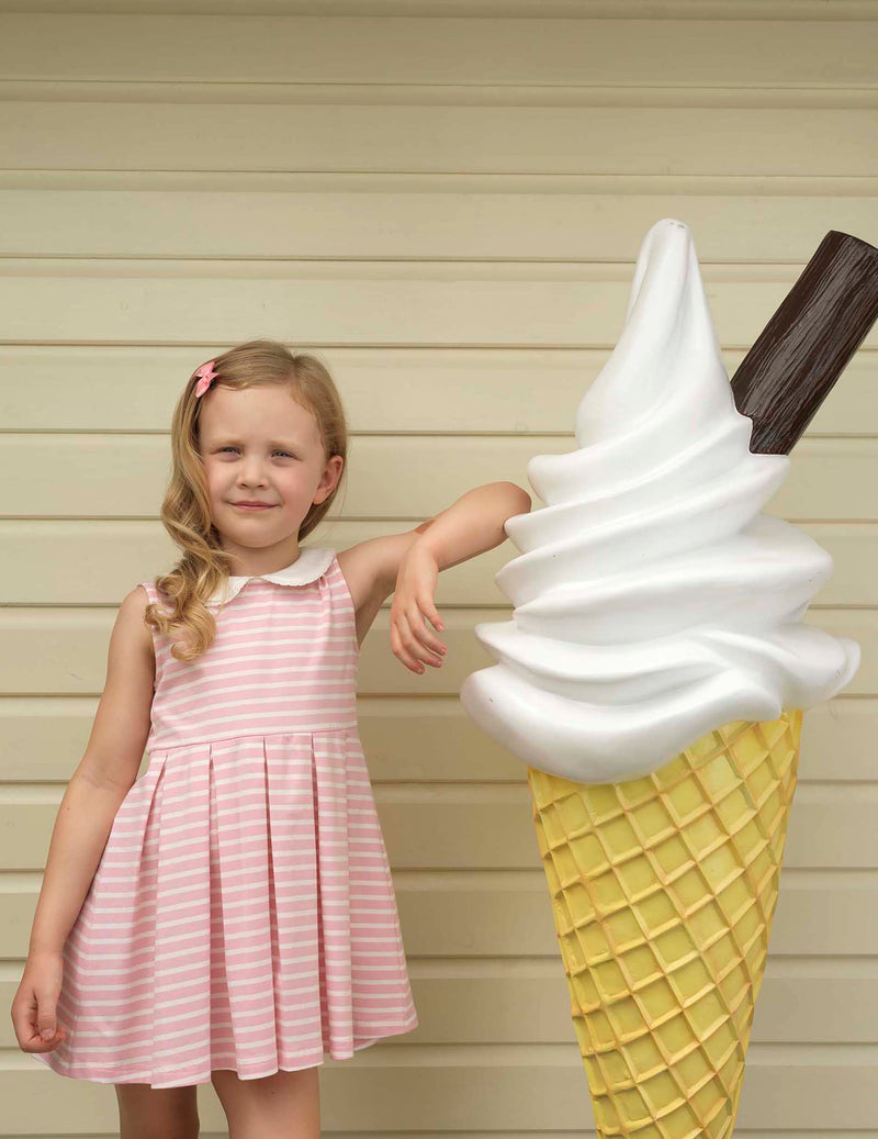 Girl in pink and ivory striped jersey dress, with pleated skirt and contrasting peter pan collar.