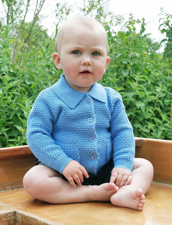 Baby boy wearing blue moss stitch cardigan, styled with navy shorts.