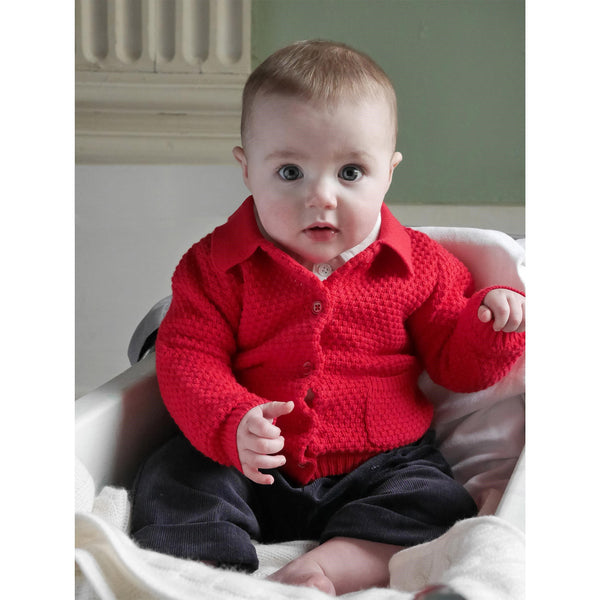 Baby boy wearing red moss stitch cardigan, styled with brown babycord trousers.
