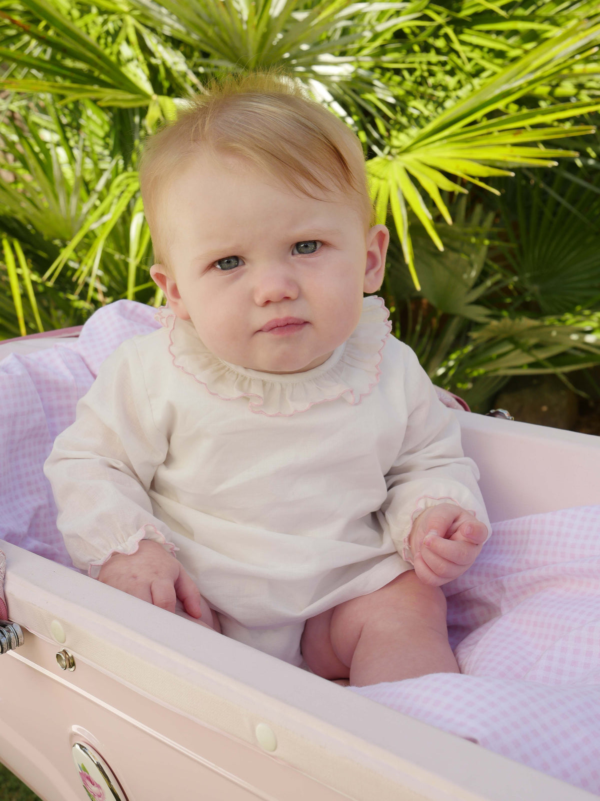 Baby in pink trim frill collar blouse with jersey body underneath and long sleeves.