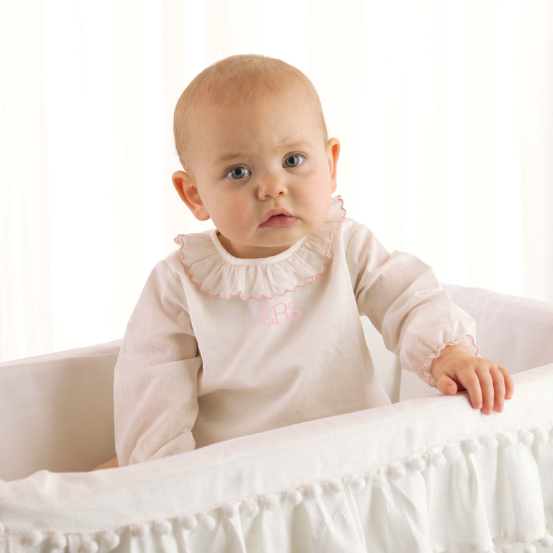Baby in pink trim frill collar blouse with jersey body underneath and long sleeves.