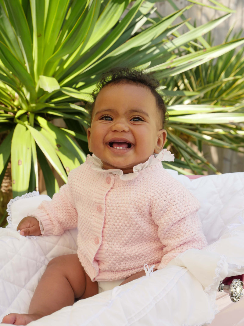 Baby girl wearing pink round neck moss stitch cardigan and pink trimmed frill collar body