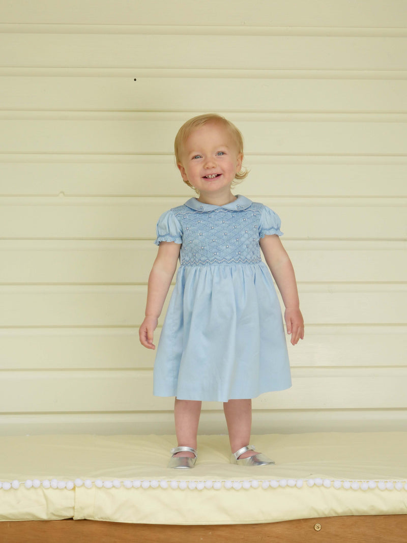 Babies blue dress with smocked bodice, embroidered with roses, peter pan collar and gathered skirt.