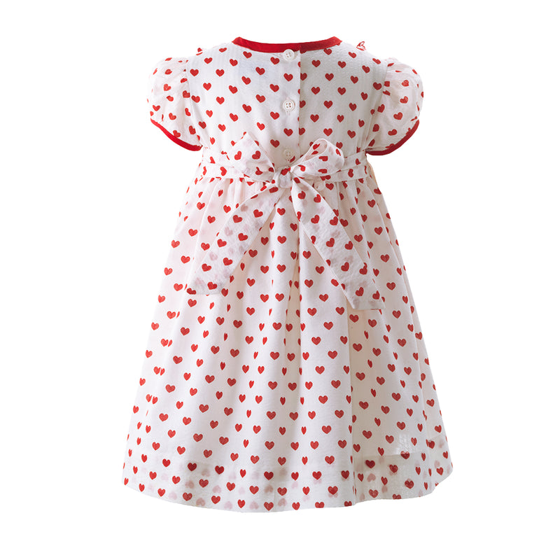 Baby ivory dress with red heart print and frill detail at the bodice, red trim and sash tie