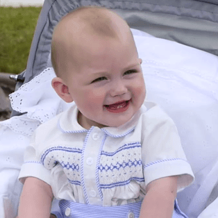Baby boy in blue smocked, short sleeved shirt and matching blue striped button on short set